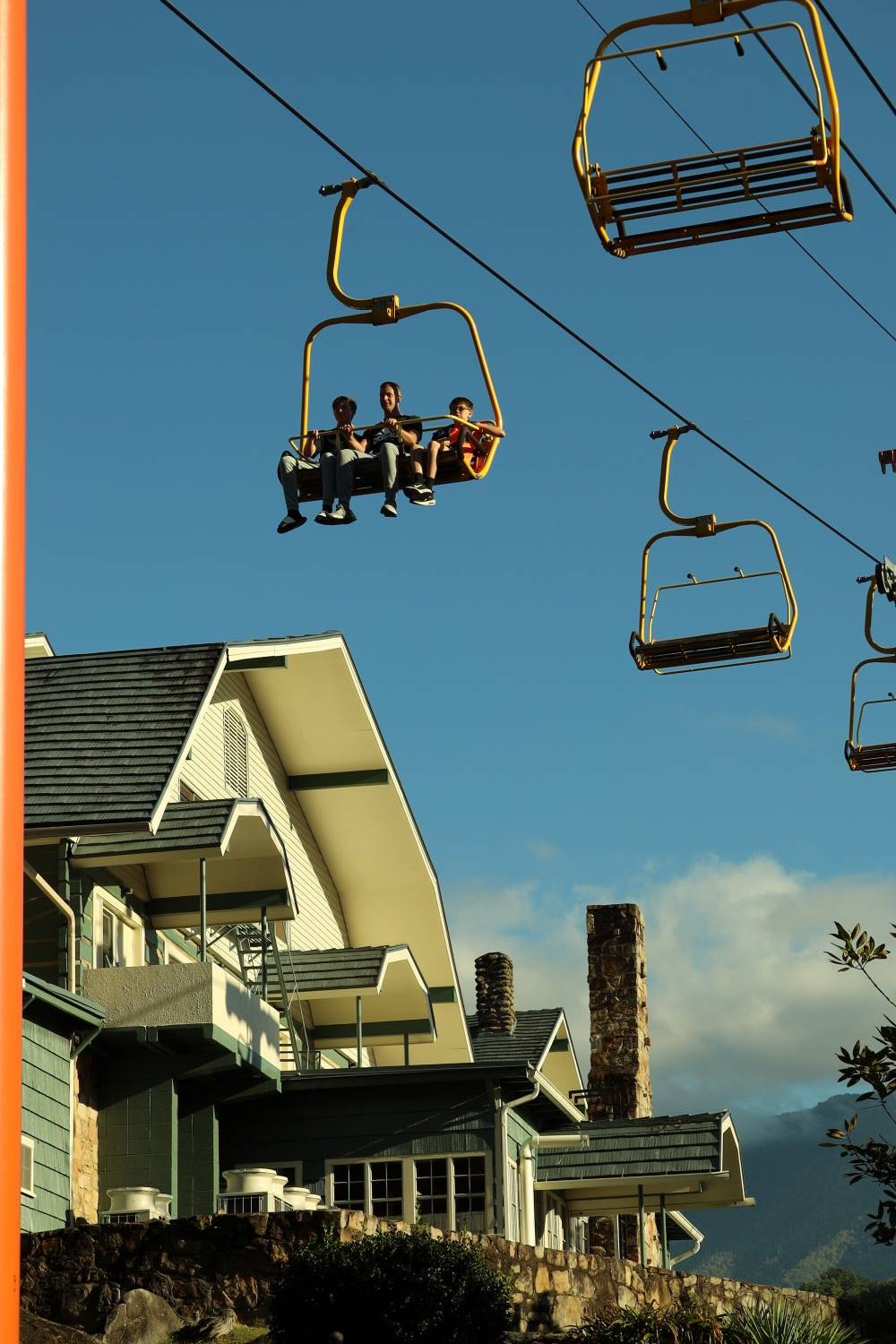 Gatlinburg SkyLift chairs passing over the Historic Gatlinburg Inn under a blue sky