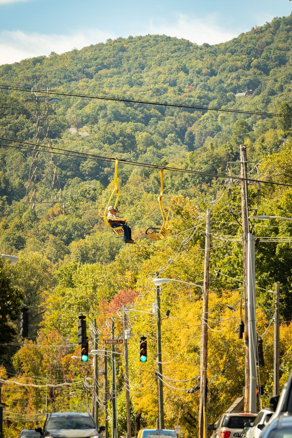 Gatlinburg SkyLift chair rising above the Parkway with fall color on the mountain